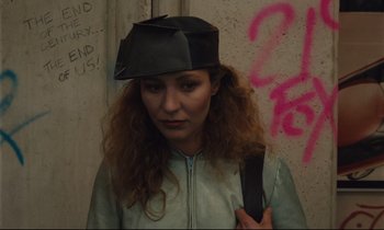 Movie still from “Until the End of the World” (1991), directed by Wim Wenders – A woman wearing a hat and holding a cell phone; Close Up shot, High angle
