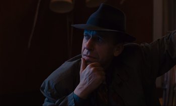 Movie still from “Until the End of the World” (1991), directed by Wim Wenders – A man wearing a hat and a jacket; Close Up shot, Over the shoulder angle
