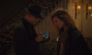 Movie still from “Until the End of the World” (1991), directed by Wim Wenders – A man and a woman looking at a cell phone; Medium shot, Over the shoulder angle