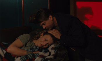 Movie still from “Until the End of the World” (1991), directed by Wim Wenders – A man and a woman laying on a bed; Medium shot, Over the shoulder angle