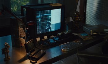Movie still from “Until the End of the World” (1991), directed by Wim Wenders – A computer monitor sitting on top of a wooden desk; Medium shot, High angle