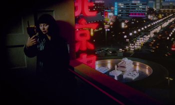 Movie still from “Until the End of the World” (1991), directed by Wim Wenders – A woman standing in front of an illuminated wall; Wide shot, High angle