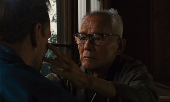 Movie still from “Until the End of the World” (1991), directed by Wim Wenders – An older man with glasses is looking at a younger man; Close Up shot, Over the shoulder angle