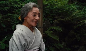 Movie still from “Until the End of the World” (1991), directed by Wim Wenders – An older woman wearing a kimono smiling for the camera; Close Up shot, Low angle