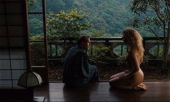 Movie still from “Until the End of the World” (1991), directed by Wim Wenders – A man and a woman sitting on the floor of a house; Wide shot, High angle