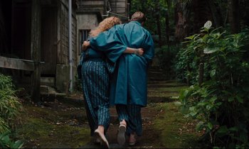 Movie still from “Until the End of the World” (1991), directed by Wim Wenders – Two women walking down a path holding each other; Wide shot, High angle