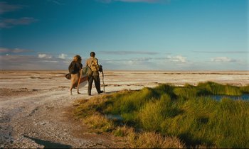 Movie still from “Until the End of the World” (1991), directed by Wim Wenders – A man and a woman are walking in the desert; Extreme Wide shot, Low angle