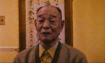 Movie still from “Until the End of the World” (1991), directed by Wim Wenders – An older man wearing a suit and tie; Close Up shot, Low angle