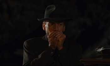 Movie still from “Until the End of the World” (1991), directed by Wim Wenders – A man in a black hat is smoking a cigarette; Close Up shot, Over the shoulder angle