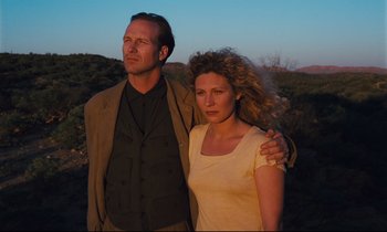 Movie still from “Until the End of the World” (1991), directed by Wim Wenders – A man and a woman standing next to each other; Medium shot, Low angle