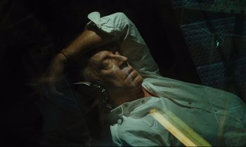 Movie still from “Until the End of the World” (1991), directed by Wim Wenders – A man laying on a bed with his head on a pillow; Close Up shot, Overhead angle