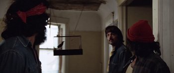 Movie still from “Up in Smoke” (1978), directed by Lou Adler – A man standing next to a bird in a cage; Medium shot, Low angle