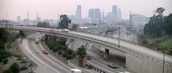 Cars driving on a freeway with a city skyline in the background