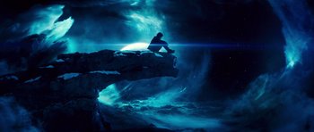 A man sitting on top of a rock in front of the moon