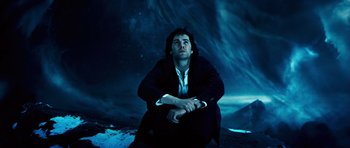 A man sitting on the ground looking up at the night sky