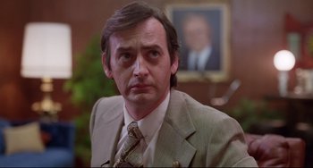 Movie still from “Used Cars” (1980), directed by Robert Zemeckis – A person wearing a suit and tie; Close Up shot, Low angle