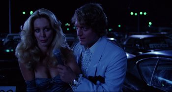 Movie still from “Used Cars” (1980), directed by Robert Zemeckis – A man and a woman dressed in formal wear; Medium shot, Low angle