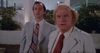 Movie still from “Used Cars” (1980), directed by Robert Zemeckis – Two men in suits and ties standing next to each other; Medium shot, Low angle