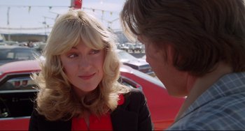 Movie still from “Used Cars” (1980), directed by Robert Zemeckis – A woman and a man talking to each other outside; Close Up shot, Over the shoulder angle