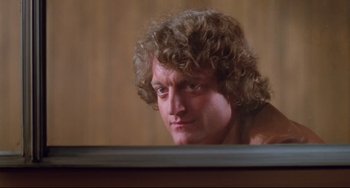 Movie still from “Used Cars” (1980), directed by Robert Zemeckis – A person sitting at a table; Close Up shot, Low angle