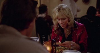 Movie still from “Used Cars” (1980), directed by Robert Zemeckis – A woman sitting at a table with a plate of food; Close Up shot, Over the shoulder angle