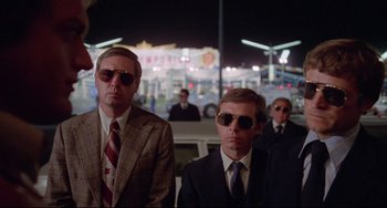 Movie still from “Used Cars” (1980), directed by Robert Zemeckis – A group of men in suits and sunglasses; Medium shot, Low angle