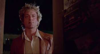 Movie still from “Used Cars” (1980), directed by Robert Zemeckis – A young man with spiky blond hair is standing outside; Close Up shot, Low angle