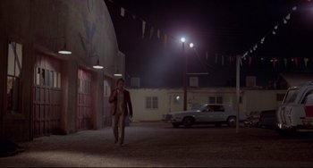 Movie still from “Used Cars” (1980), directed by Robert Zemeckis – A man walking down a street at night; Wide shot, Low angle