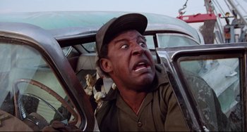 Movie still from “Used Cars” (1980), directed by Robert Zemeckis – A man in a hat is sitting in the back of a car; Close Up shot, Low angle