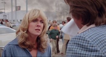 Movie still from “Used Cars” (1980), directed by Robert Zemeckis – A woman with blonde curly hair is talking to another woman; Close Up shot, Over the shoulder angle