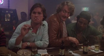 Movie still from “Used Cars” (1980), directed by Robert Zemeckis – A group of men sitting at a table with drinks; Medium shot, Low angle