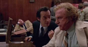 Movie still from “Used Cars” (1980), directed by Robert Zemeckis – Two men in suits and ties sitting next to each other in a courtroom; Medium shot, Over the shoulder angle