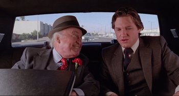 Movie still from “Used Cars” (1980), directed by Robert Zemeckis – Two men sitting in the back seat of a car; Close Up shot, Over the shoulder angle