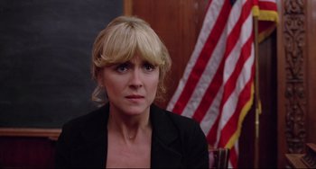 Movie still from “Used Cars” (1980), directed by Robert Zemeckis – A woman in a black jacket is in front of an american flag; Close Up shot, Low angle