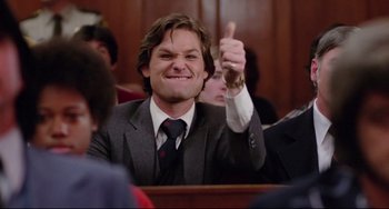 Movie still from “Used Cars” (1980), directed by Robert Zemeckis – A man giving a thumbs up while sitting in a court room; Close Up shot, Low angle