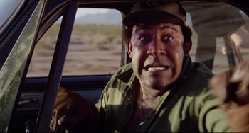 Movie still from “Used Cars” (1980), directed by Robert Zemeckis – A person driving a car in the desert; Close Up shot, Low angle