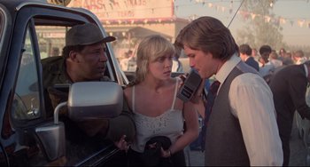 Movie still from “Used Cars” (1980), directed by Robert Zemeckis – A man and a woman talking to a man in a car; Medium shot, Over the shoulder angle