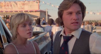 Movie still from “Used Cars” (1980), directed by Robert Zemeckis – A man and a woman standing next to each other in a parking lot; Close Up shot, Low angle