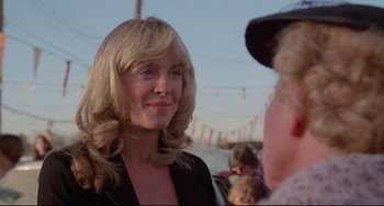 Movie still from “Used Cars” (1980), directed by Robert Zemeckis – A woman with blonde hair talking to a man in a baseball cap; Close Up shot, Over the shoulder angle