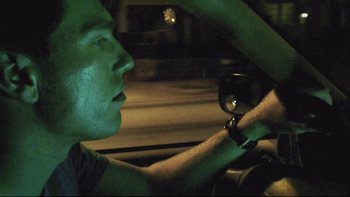 Movie still from “V/H/S” (2012), directed by Joe Swanberg – A man driving a car at night in the dark; Close Up shot, Low angle
