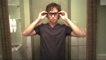 Movie still from “V/H/S” (2012), directed by Joe Swanberg – A young man wearing glasses in a bathroom; Close Up shot, Overhead angle