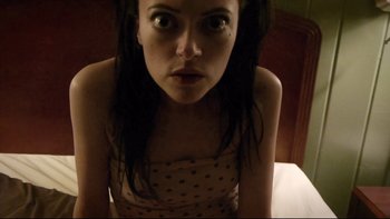 Movie still from “V/H/S” (2012), directed by Joe Swanberg – A woman with long black hair is sitting on a bed; Close Up shot, Overhead angle