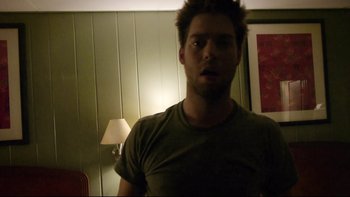 Movie still from “V/H/S” (2012), directed by Joe Swanberg – A person in a room with a lamp; Medium shot, Low angle