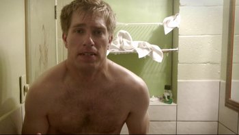 Movie still from “V/H/S” (2012), directed by Joe Swanberg – A man in a bathroom taking a picture of himself in the mirror; Close Up shot, Low angle