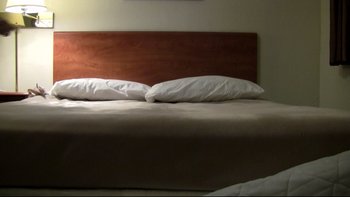 Movie still from “V/H/S” (2012), directed by Joe Swanberg – A bed with a wooden headboard and two pillows on it; Wide shot, High angle