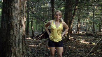 Movie still from “V/H/S” (2012), directed by Joe Swanberg – A woman standing in the middle of a forest; Wide shot, Low angle