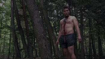 Movie still from “V/H/S” (2012), directed by Joe Swanberg – A man with a tie in the middle of a forest; Medium shot, Low angle