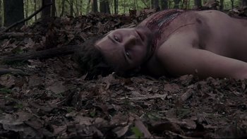 Movie still from “V/H/S” (2012), directed by Joe Swanberg – A man laying on the ground in the leaves; Medium shot, Overhead angle
