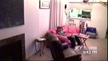 Movie still from “V/H/S” (2012), directed by Joe Swanberg – A person sitting on a pink couch in a living room; Wide shot, High angle