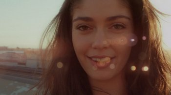 Movie still from “V/H/S Viral” (2014), directed by Aaron Moorhead – A young woman's face with sun shining in the background; Close Up shot, Low angle